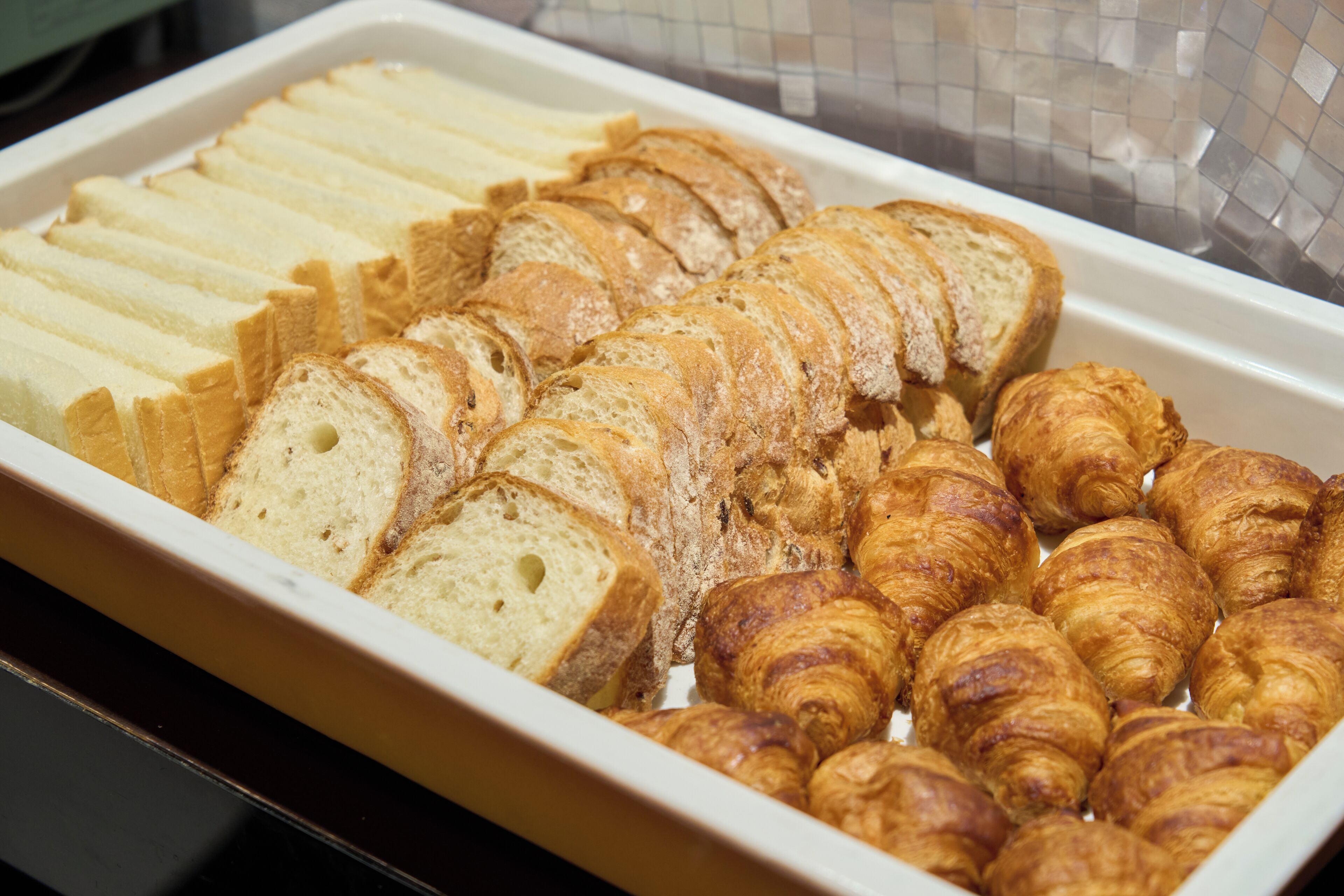 A tray of sliced bread and croissants.