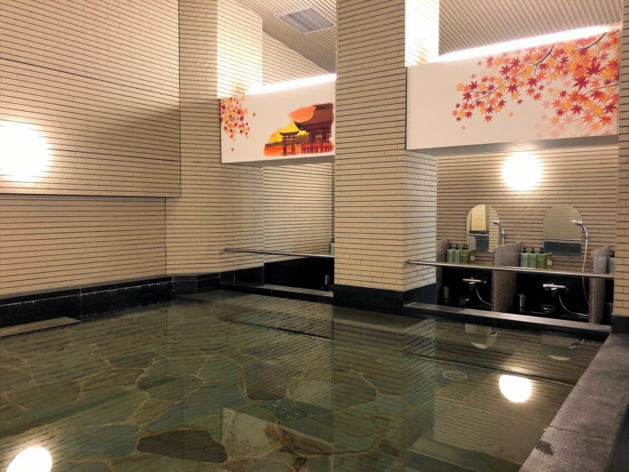 Un área de piscina interior moderna con suelo de piedra y pared de madera con diseño de hojas.
