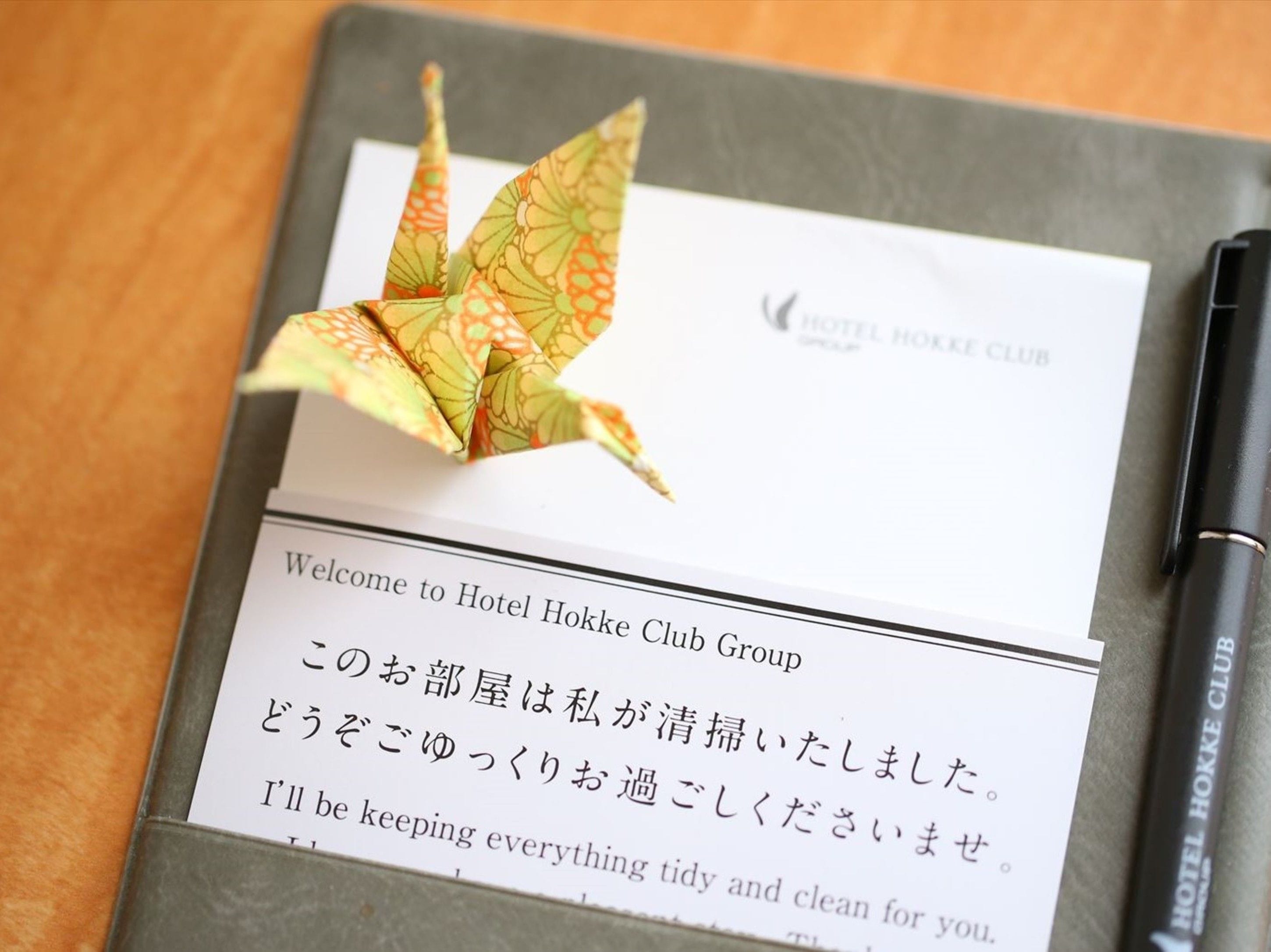 A business card from Hotel Hokkke Club Group with a Japanese greeting and a note about keeping the room tidy.