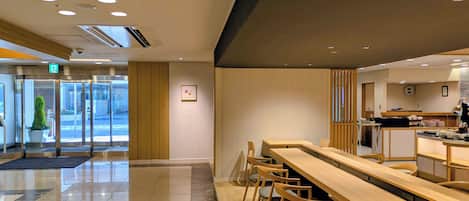 Un vestíbulo moderno de hotel con mostrador de recepción, zona de estar y puerta de entrada de vidrio.