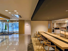 Un vestíbulo moderno de hotel con mostrador de recepción, zona de estar y puerta de entrada de vidrio.