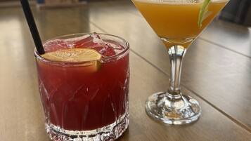 Two drinks on a table with a window view in the background.