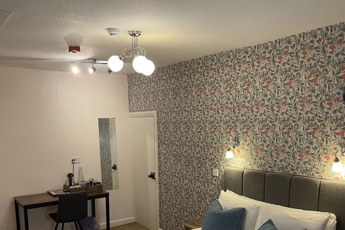 A neatly arranged hotel room with a bed, bedside lamps, a desk, and a mirror.