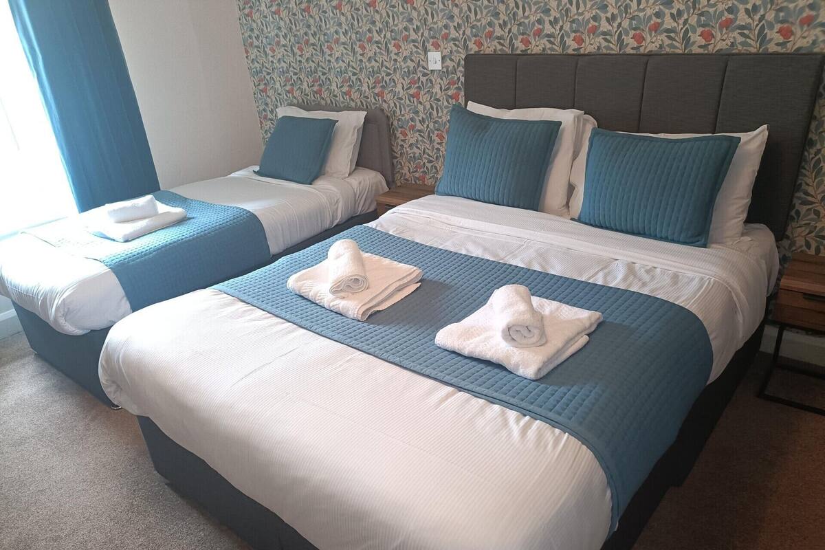 A hotel room with two beds, each with blue bedding and white towels.