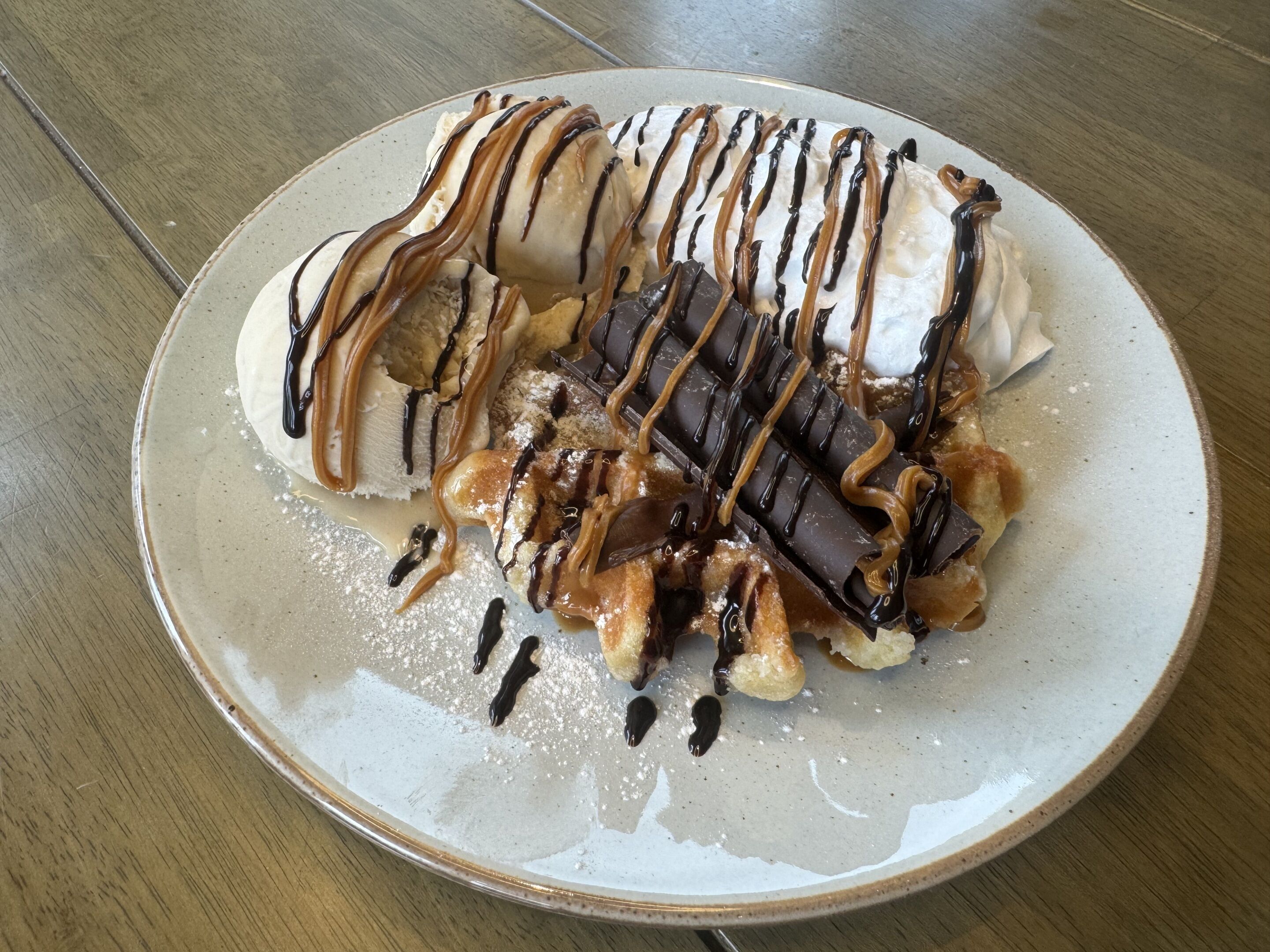 A dessert plate with ice cream, chocolate, and caramel sauce.