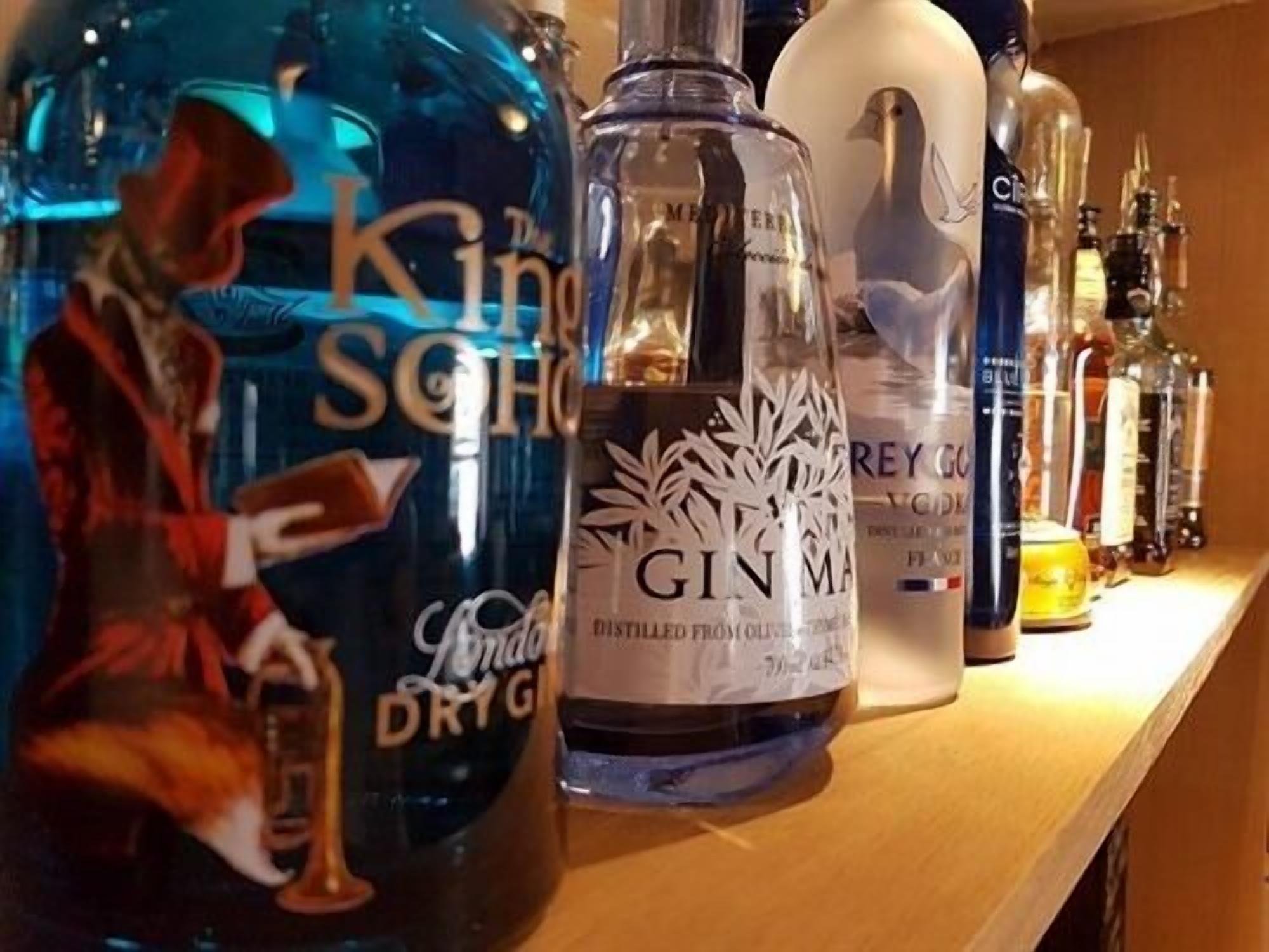 Une étagère contenant différentes bouteilles d’alcool, notamment du gin et de la vodka.