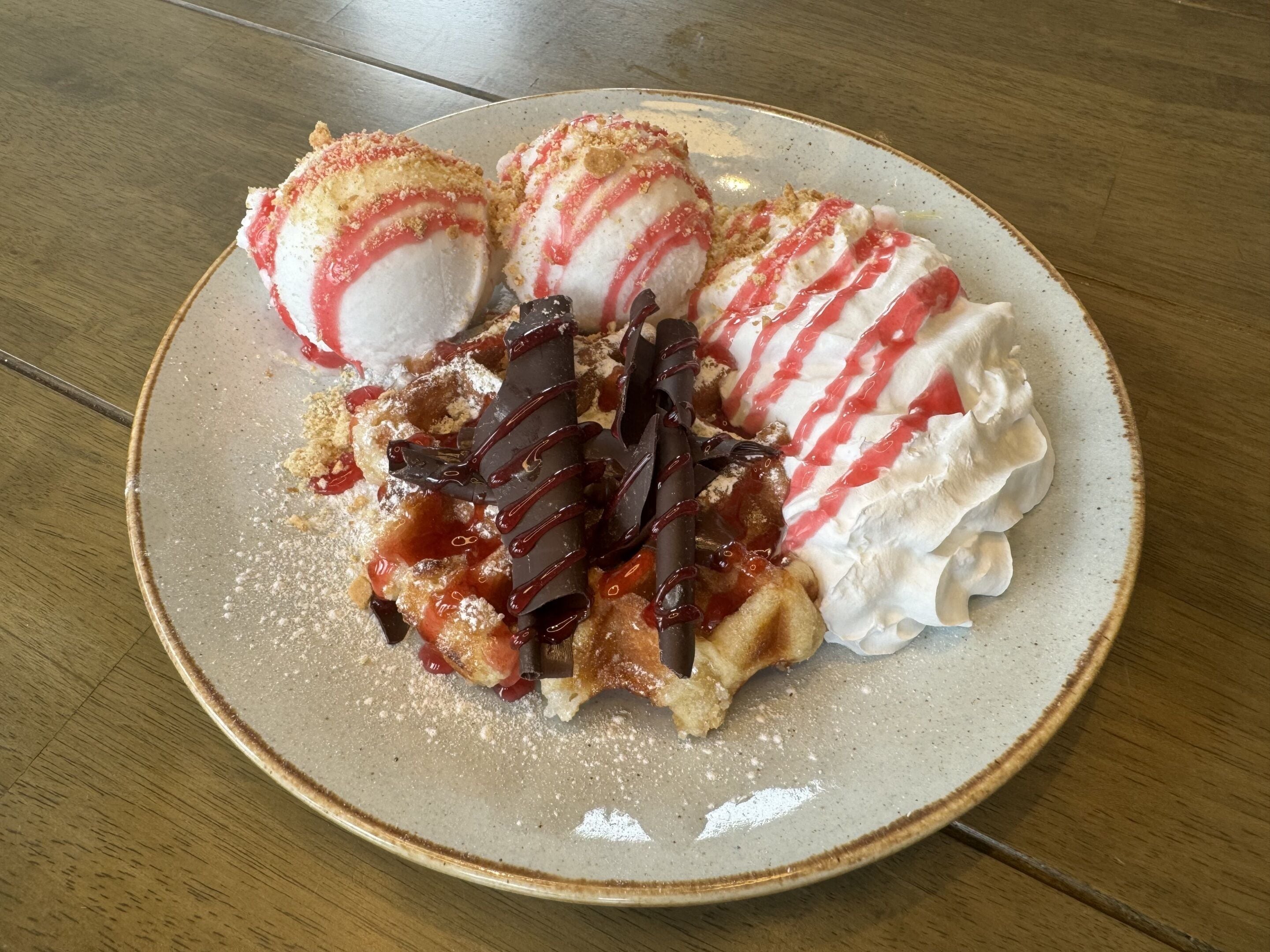 Une assiette avec trois boules de glace, une barre de chocolat et de la crème fouettée.