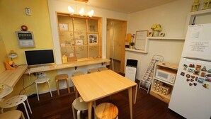 Una cocina compacta con una mesa de madera, taburetes, un refrigerador y un microondas.