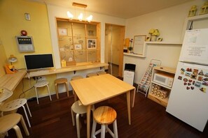 Eine kleine Küche mit Holztisch, Hockern, Kühlschrank und Mikrowelle.