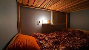Una habitación con una cama, una lámpara fijada a la pared y una ventana.