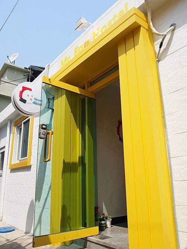 A hostel entrance with a yellow and green door, a satellite dish, and a small window. - 710 Guest house Yellow (Busan)