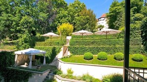 Un jardín ajardinado con un porche, setos bien recortados y una escalera que lleva a un edificio.