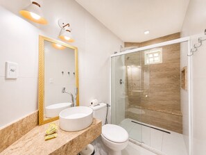A modern bathroom with a large mirror, a round sink, a toilet, and a glass-enclosed shower. - Pousada Aconchego (Cairu)