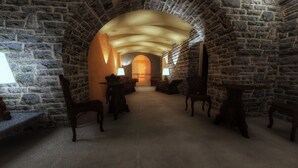 A stone-walled corridor with a high ceiling, leading to a room with a fireplace and a table with chairs. - Artis Domus Relais & Spa (Sorrento)