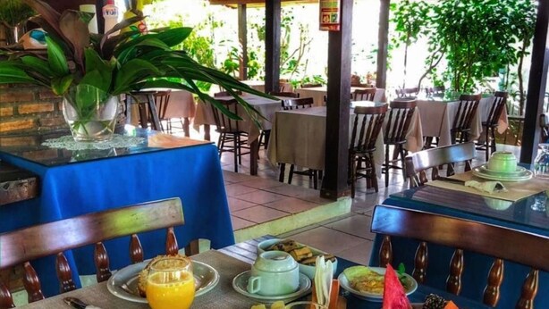 An outdoor dining area with tables set for breakfast, including plates of food, drinks, and a fire extinguisher visible. - Pousada Paraiso de Boipeba (Cairu)
