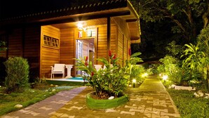 A wooden building with a covered porch, white chairs, and a pathway leading to the entrance. - Pousada Paraiso de Boipeba (Cairu)