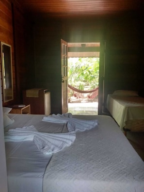 A room with two beds, a desk, and a door leading to an outdoor area with a hammock. - Pousada Paraiso de Boipeba (Cairu)