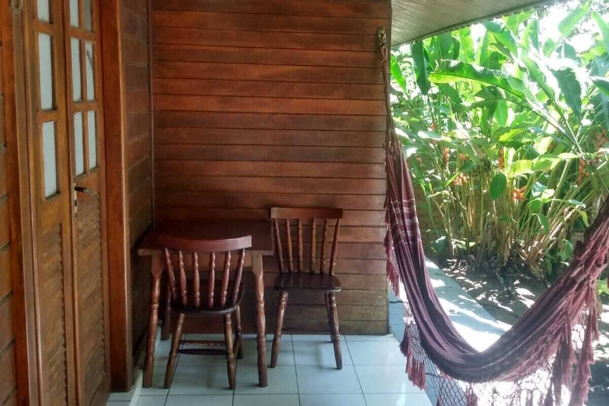 A wooden porch with two wooden chairs and a table, a hammock, and a door with glass panels.