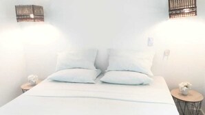 A bed with white bedding, two bedside tables with small vases, and wall-mounted light fixtures. - Pousada Paraiso de Boipeba (Cairu)