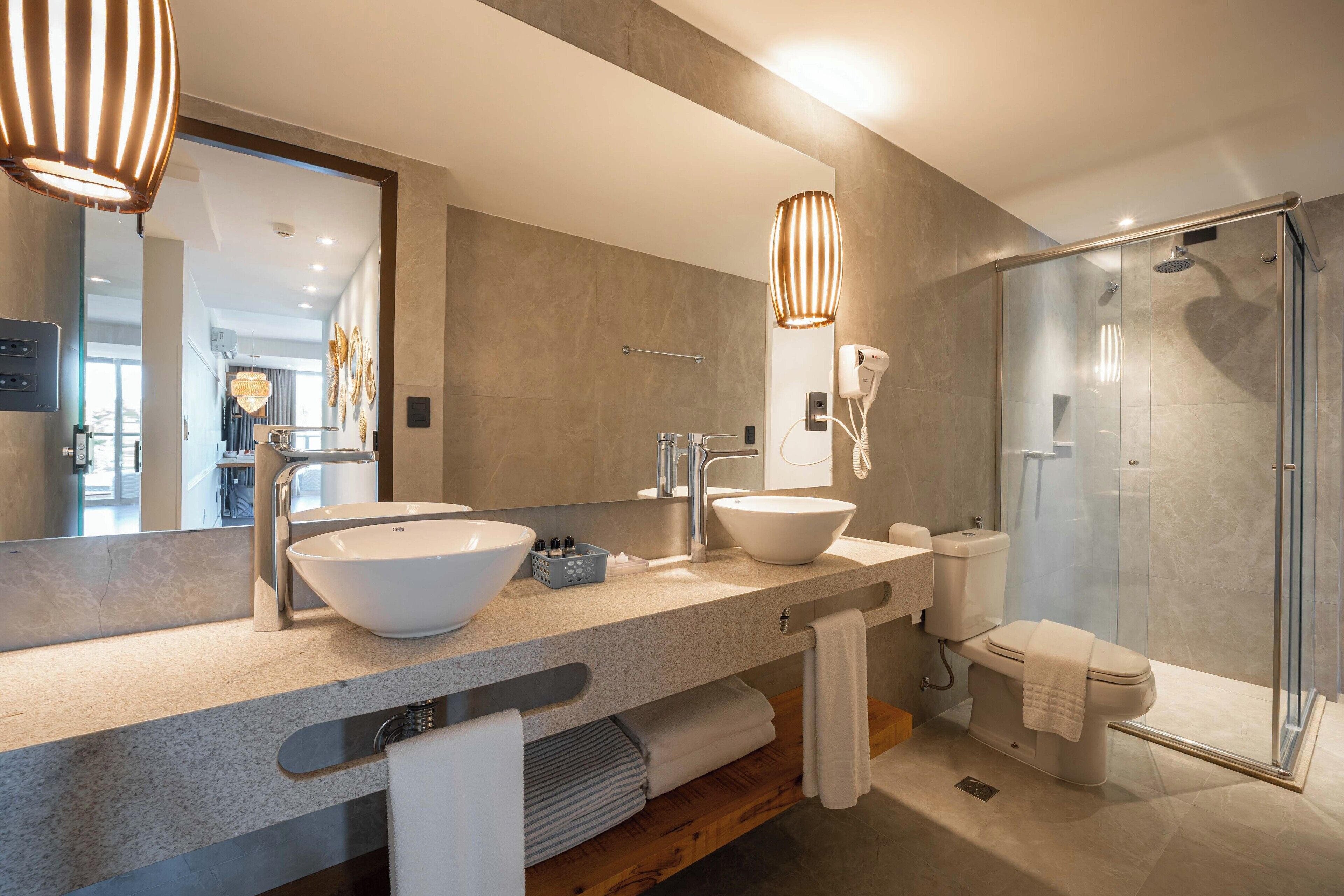 Un bagno moderno con doppio lavandino, servizi igienici e cabina doccia in vetro.