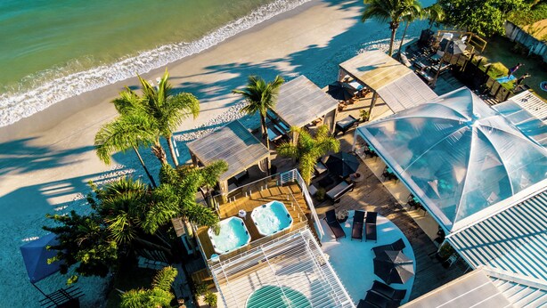 An aerial view of a resort with a pool area, sun loungers, and a beach. - Pousada dos Sonhos (Florianópolis)