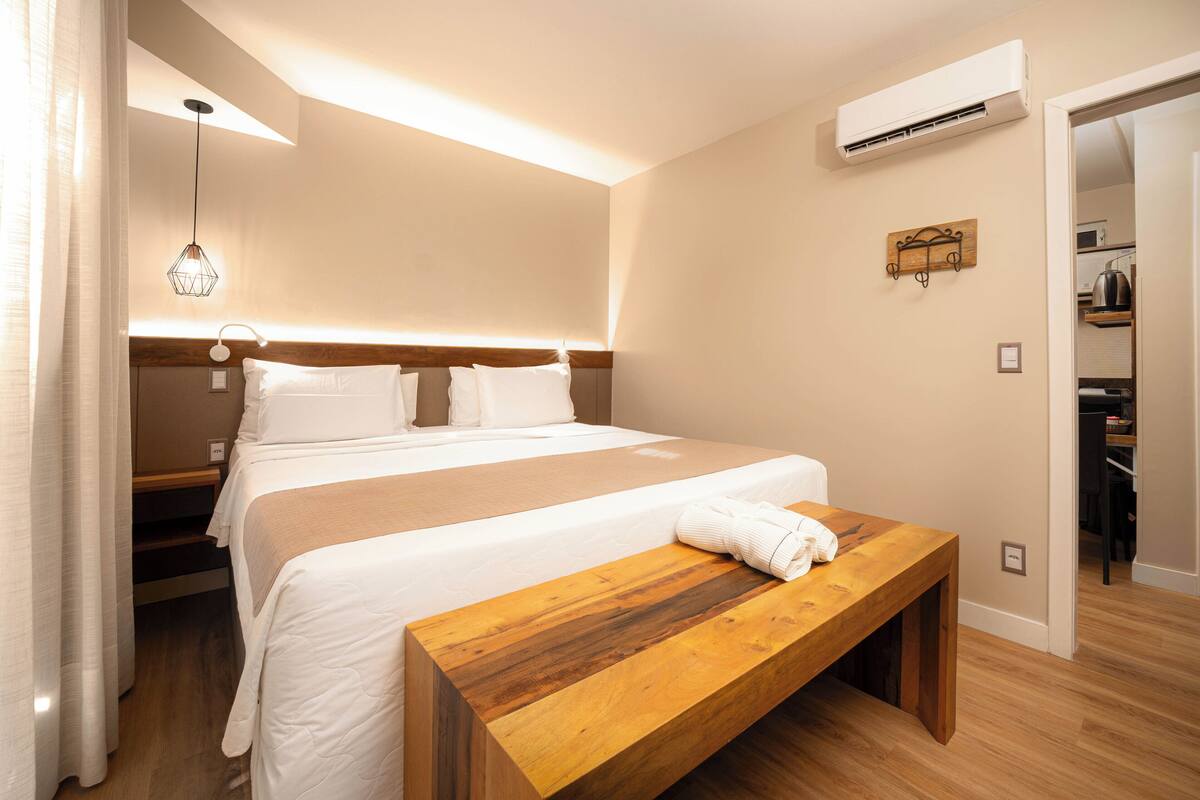 Quarto de hotel com cama, mesa de cabeceira e ar condicionado.