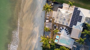An aerial view of a beachfront property with a pool, solar panels, and a patio area. - Pousada dos Sonhos (Florianópolis)
