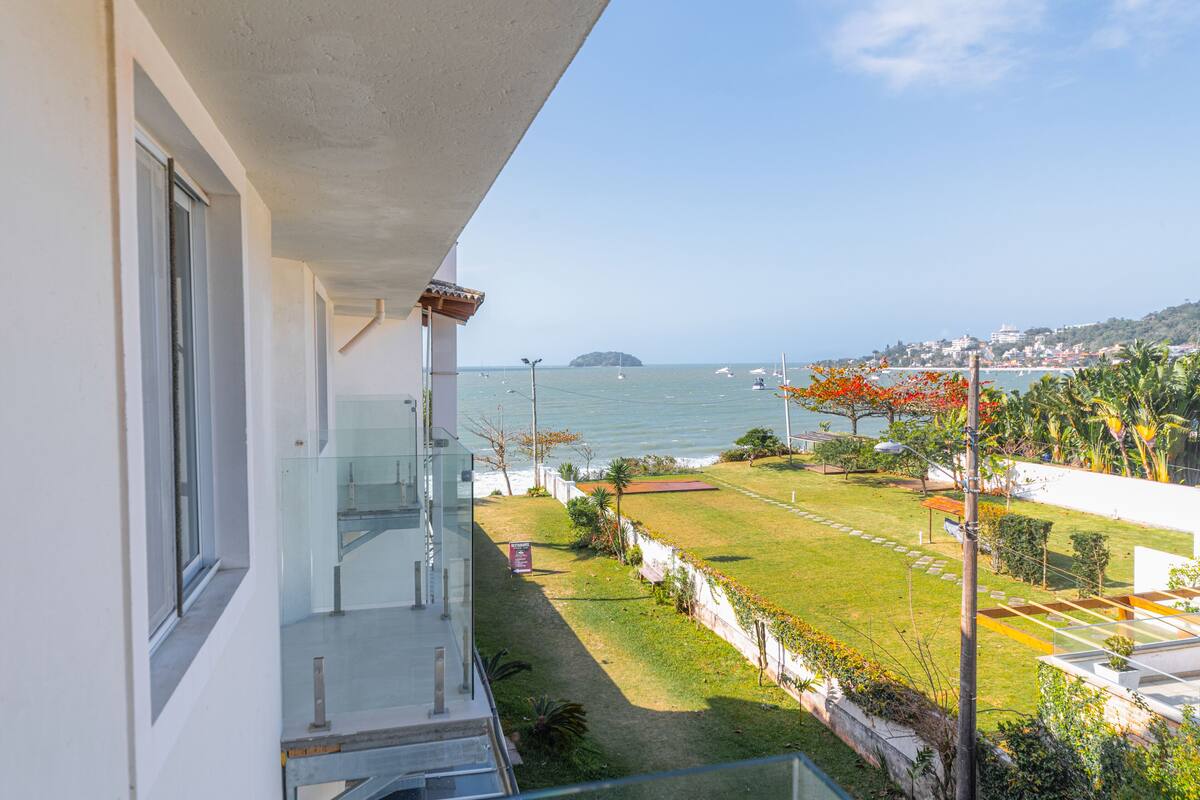 Uma varanda com vista para o mar, uma área gramada e uma ilha ao longe.