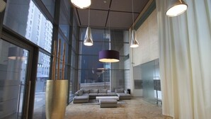 Un vestíbulo moderno con un amplio sofá modular, iluminación colgante y un jarrón grande.