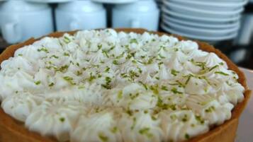 A pie with whipped cream and herbs on top.