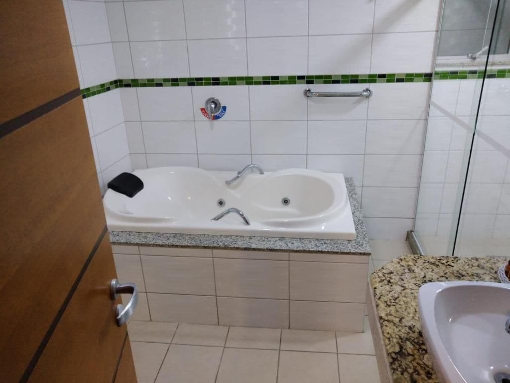 Un bagno con una vasca, un lavandino e una maniglia di sostegno.