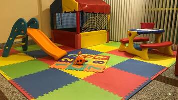 Children can play and explore in this vibrant play area featuring a playhouse, slide, and soft play zone.
