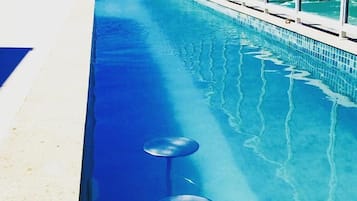 Relax by the pool surrounded by a glass barrier, with a view of the surrounding landscape.