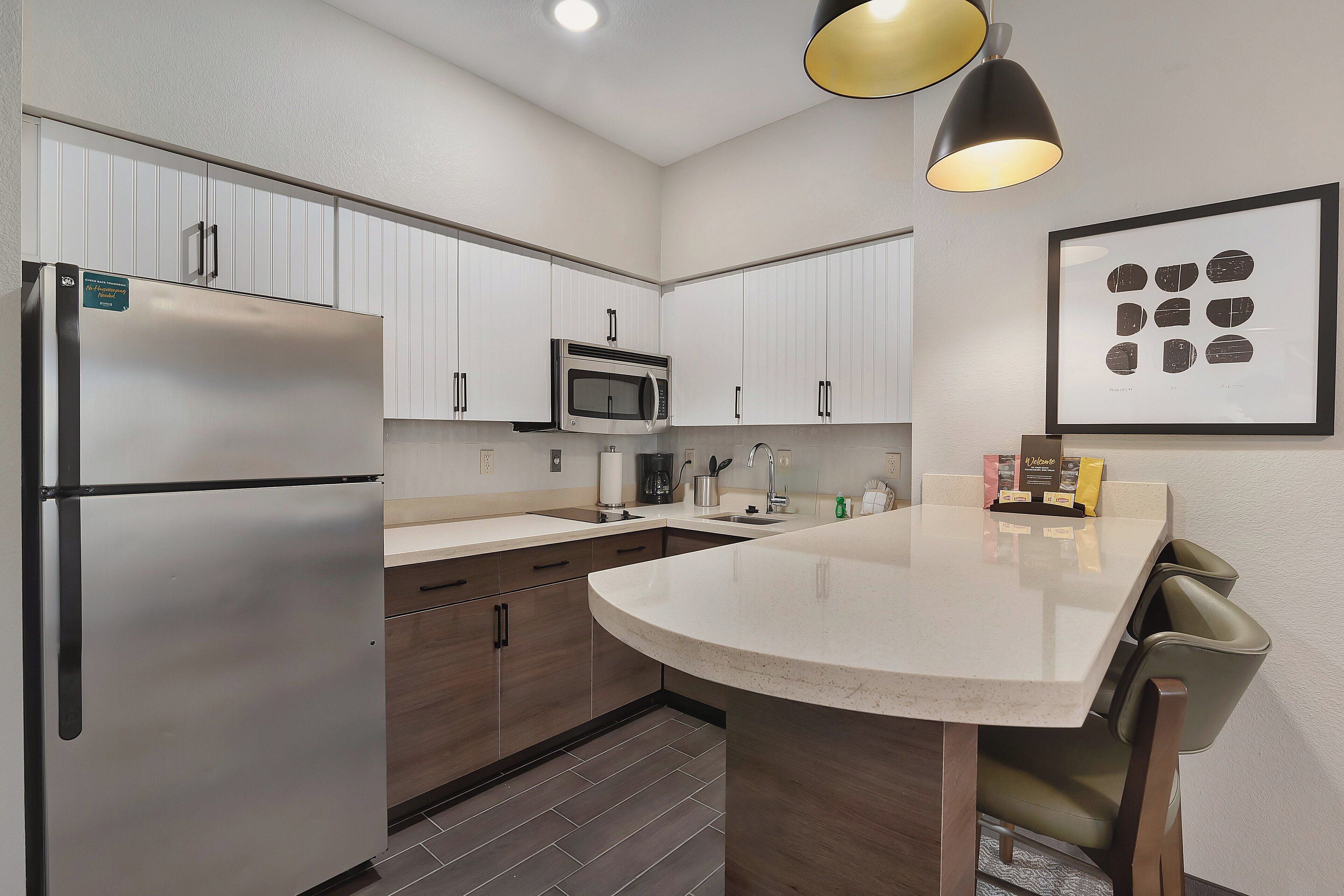 A modern kitchen with white cabinets, stainless steel appliances, and a central island with seating.