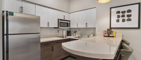 Una cocina moderna con armarios blancos, electrodomésticos de acero inoxidable y una isla central con asientos.