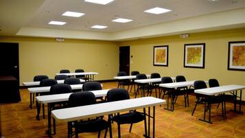 A conference room with multiple tables and chairs, a carpeted floor, and ceiling lights.