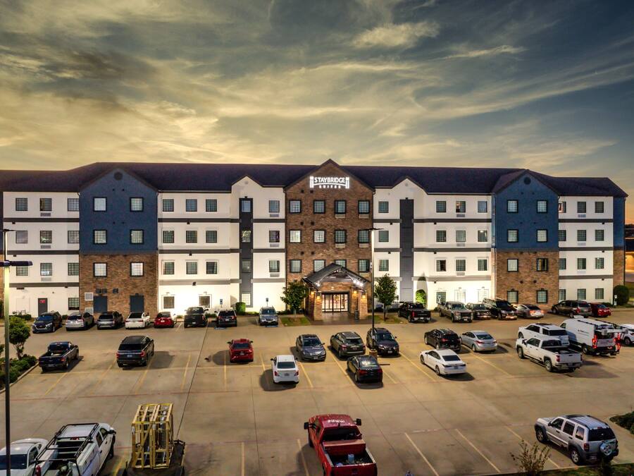 A multi-story hotel with a central entrance, parking lot, and a sign reading "STAYBRIDGE".