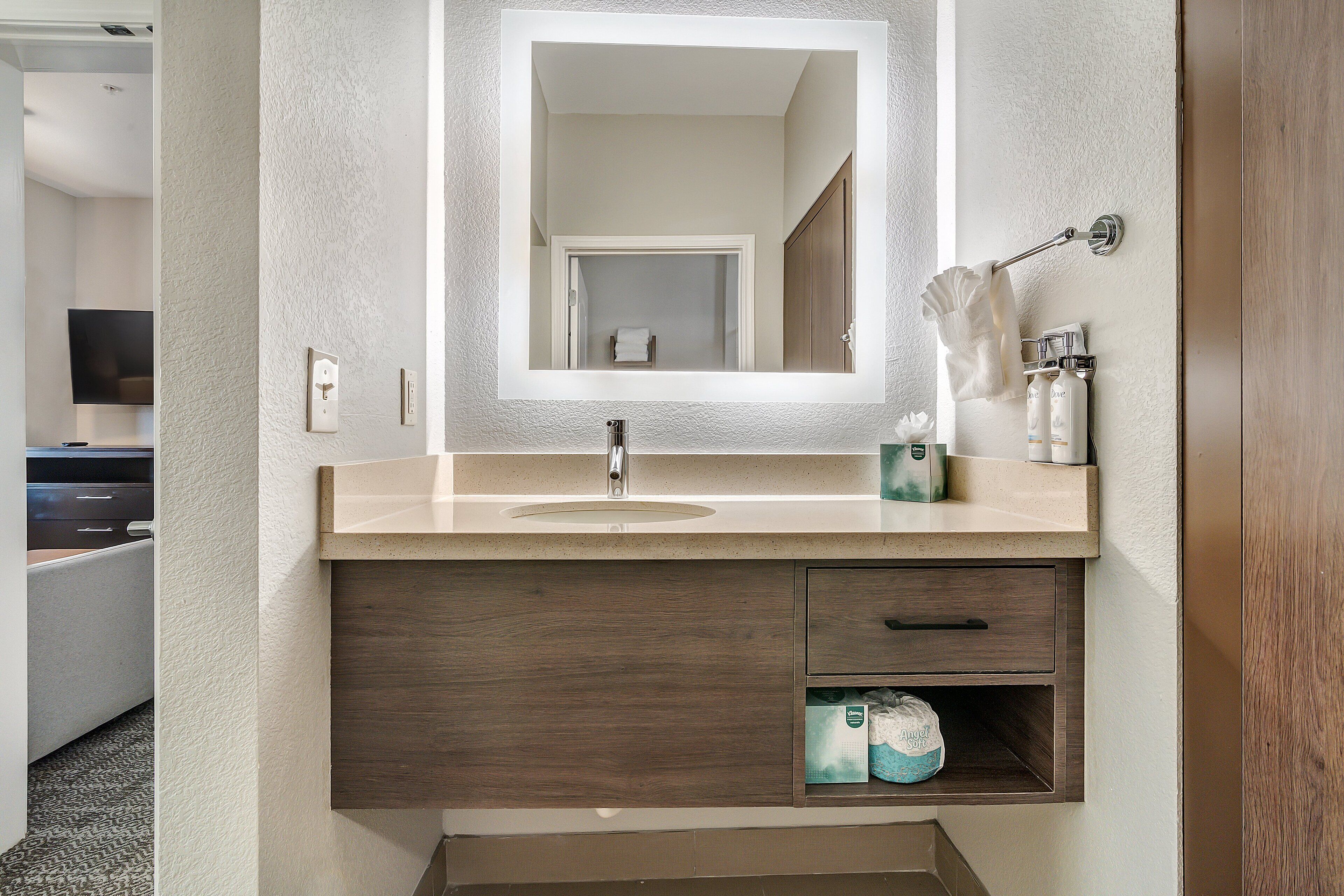 A bathroom with a sink, mirror, towel rack, and storage cabinet.