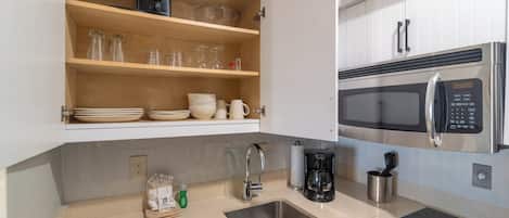 A kitchen with a stainless steel microwave, a coffee maker, and a sink.