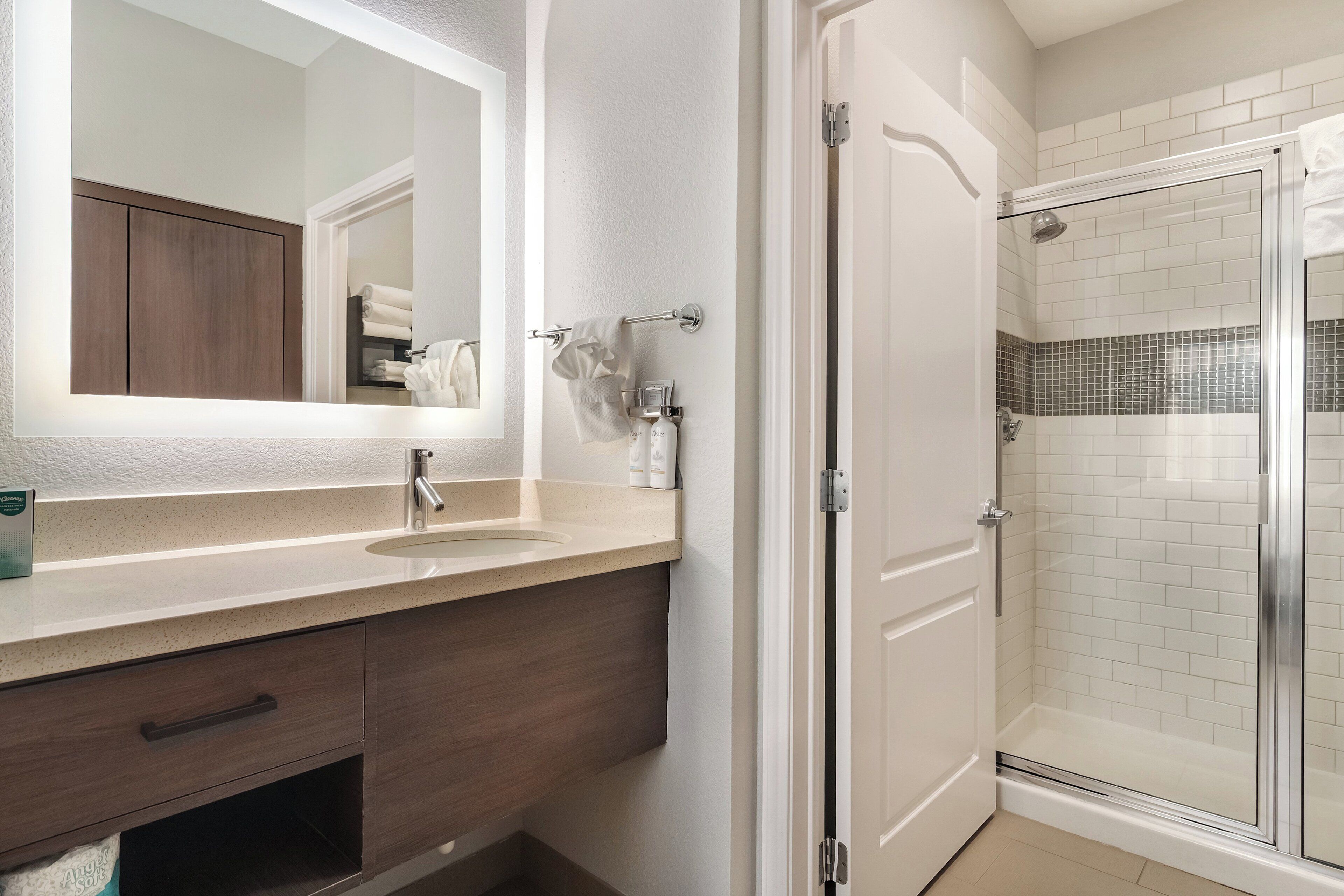 Un baño con un espejo grande, un lavabo, un armario y una zona de ducha.