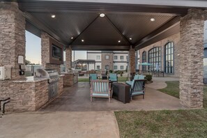 An outdoor patio with stone pillars, a grill, and seating. - Staybridge Suites Longview by IHG (Longview)