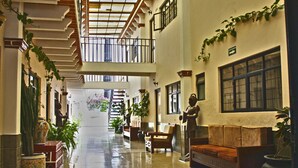 Eine großzügige Lobby mit hoher Decke, einer Treppe und einer Sitzecke mit Sofa und Sesseln.