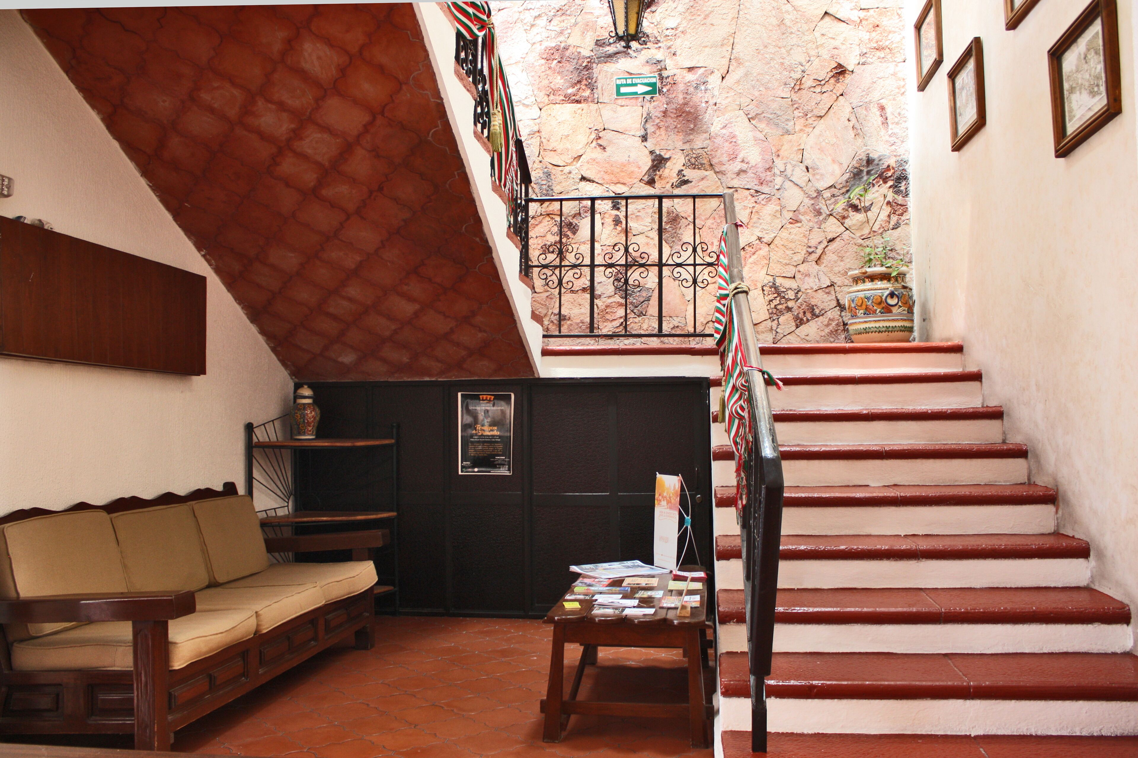 A staircase with red steps leading to a landing, a wooden bench, and a small table with books.