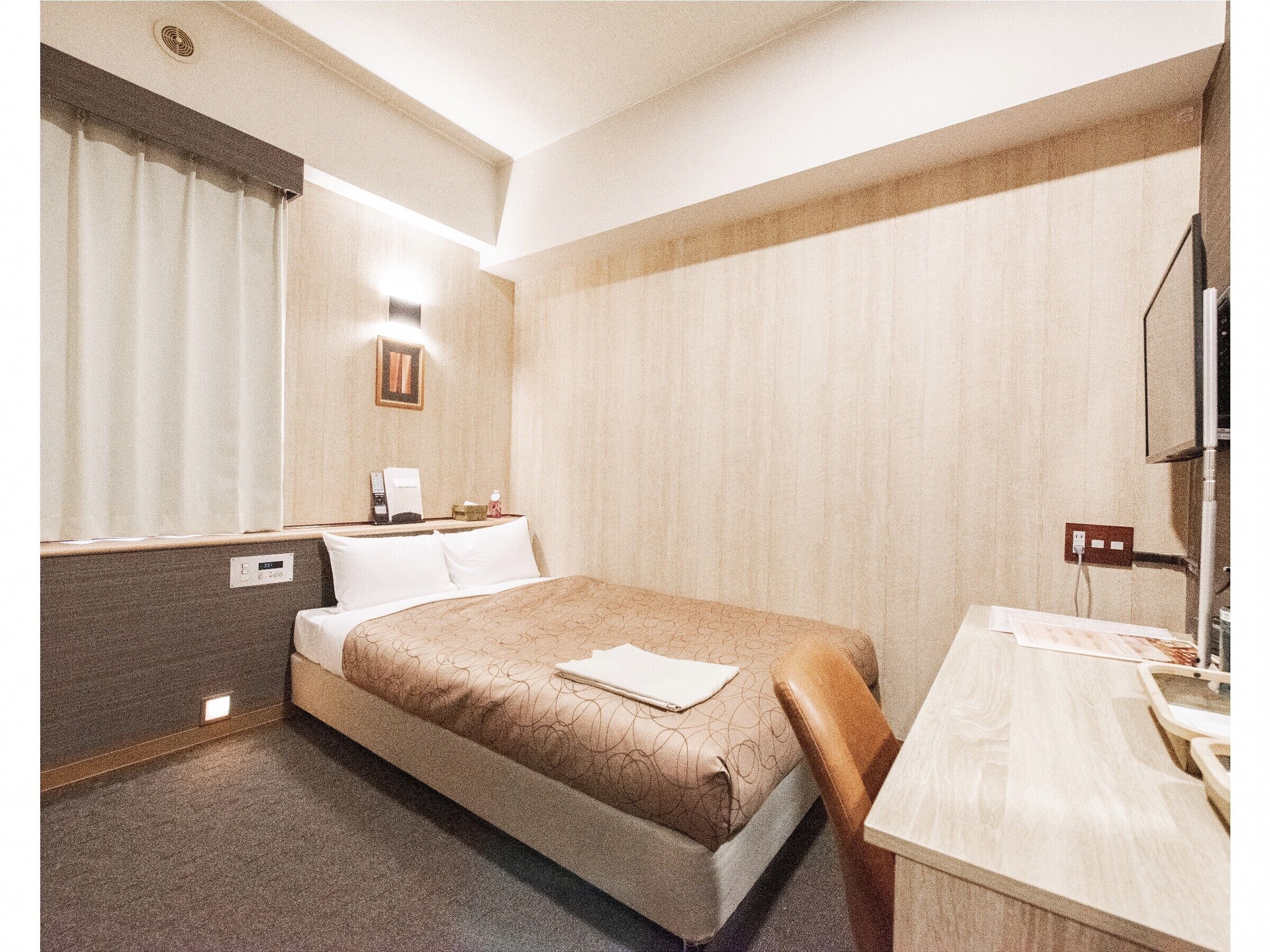 Una habitación de hotel con cama, mesita de noche, lámpara y espejo.