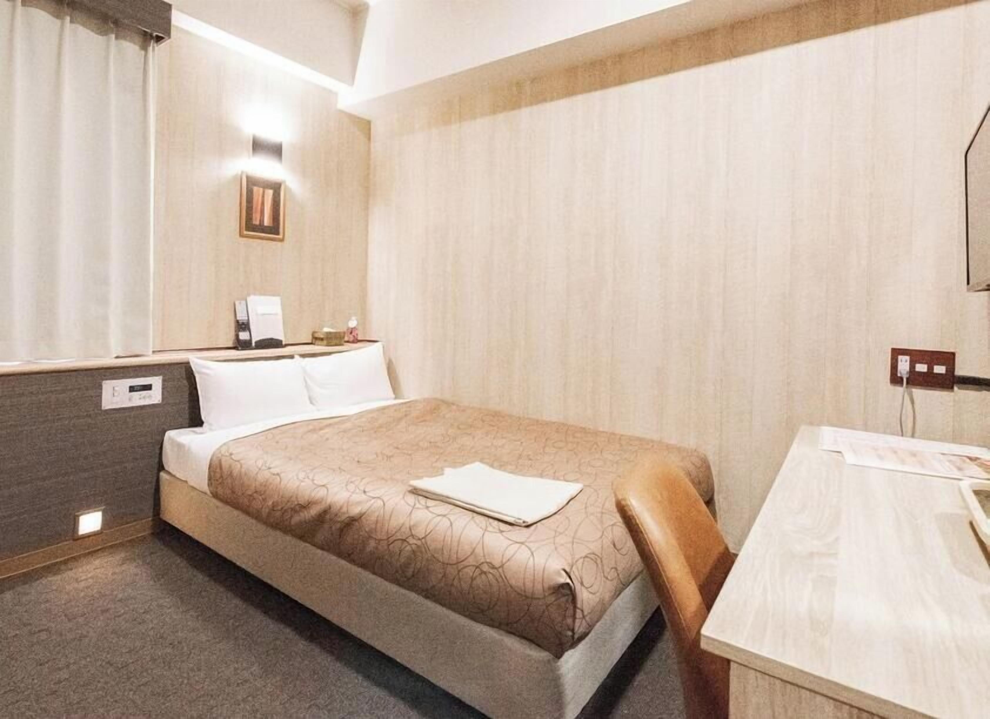 Ein Hotelzimmer mit Bett, Nachttisch und Schreibtisch.