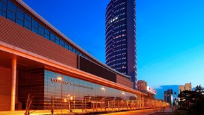 Un edificio moderno con fachada curva y una torre alta e iluminada.