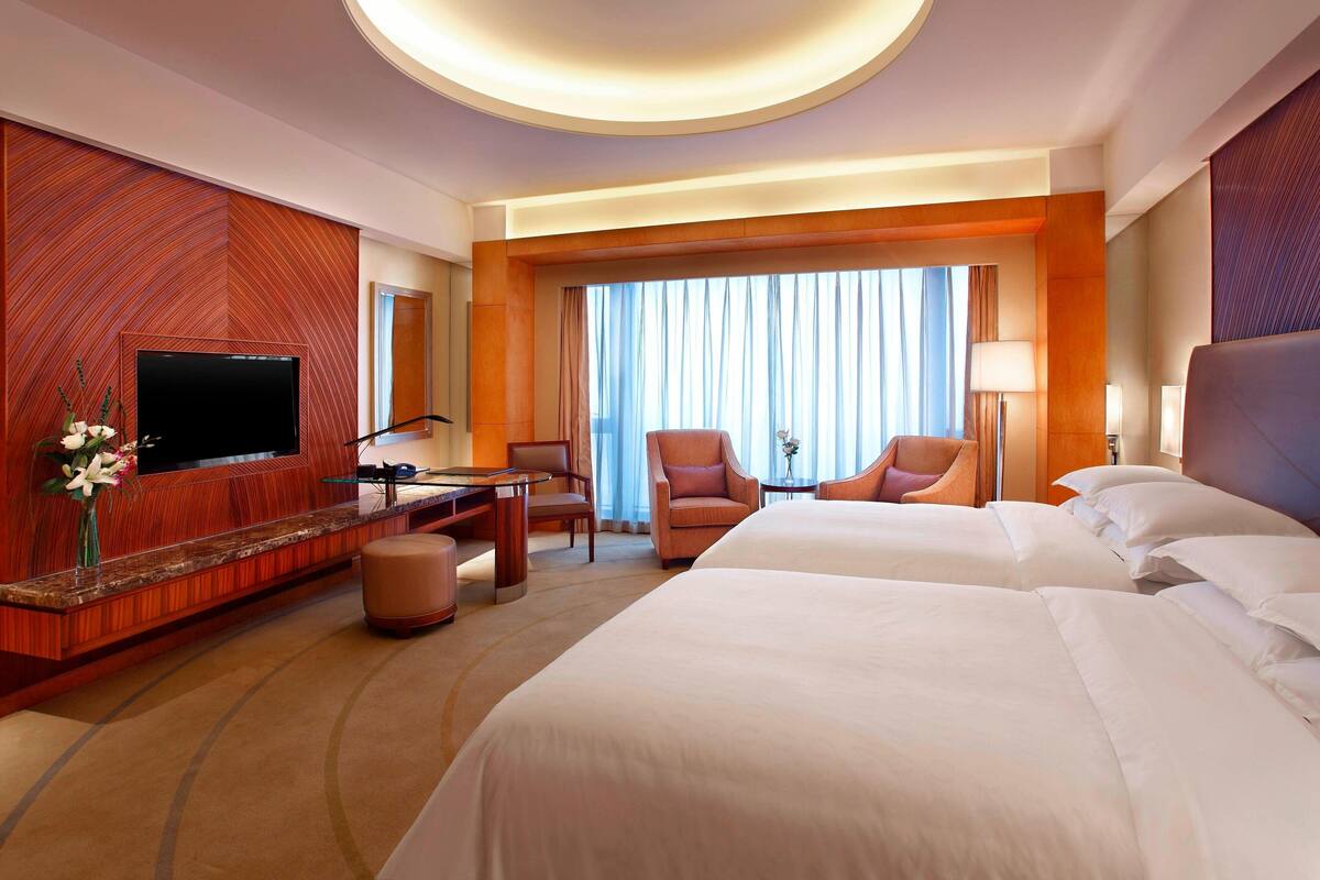 Une chambre d’hôtel avec un grand lit, une télévision, un bureau et une chaise.