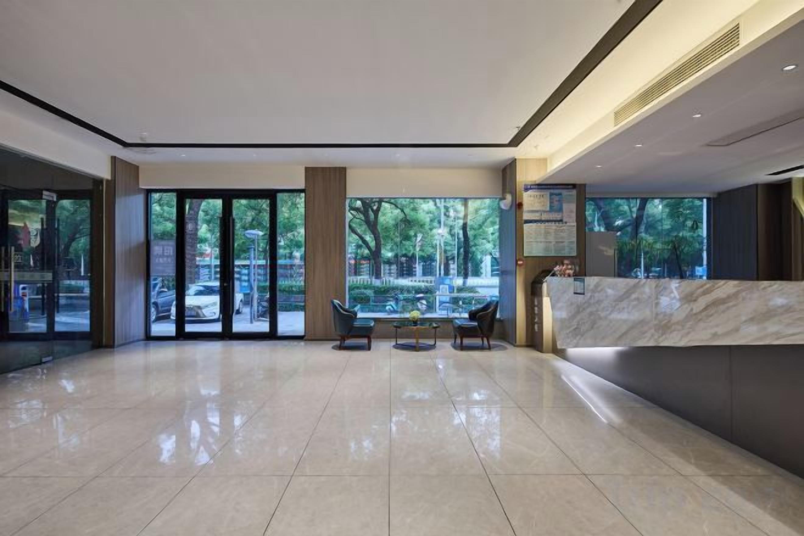 A spacious lobby with a reception desk, seating area, and large windows offering a view of the outdoors.