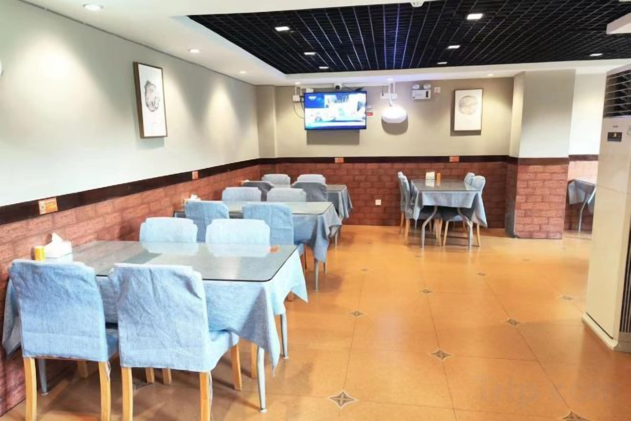A conference room with tables and chairs, a television screen, and a brick accent wall.