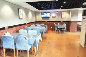 A conference room with tables and chairs, a television screen, and a brick accent wall. - Home Inn Neo (Ganzhou Hongqi Avenue South Gate) (Ganzhou)
